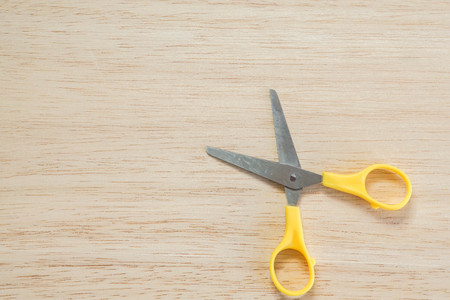 tiny cute yellow scissors on wooden background for craft workの写真素材