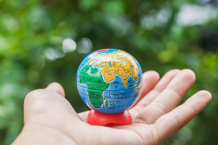 Save the world concept - globe in woman hand with tree bokeh backdropの写真素材