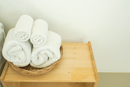 neat rolls of white cotton towel on basket in bedroomの写真素材