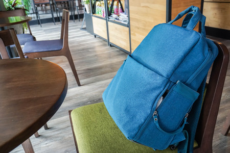 place blue small backpack bag on chair in coffee shopの写真素材