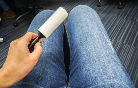 close up woman use lint roller brush from blue jeansの写真素材
