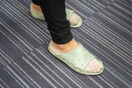 close up woman with black jeans wear green slipper in office