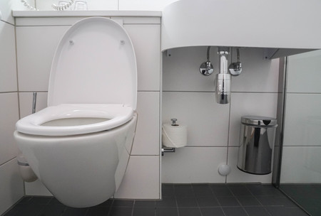 modern bathroom interior of white ceramic toilet bowl and washbasin sink with stainless bin for trashの写真素材