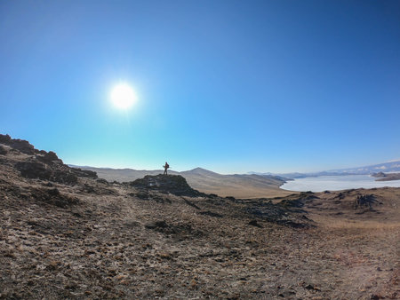 explore the world concept - man traveler on mountain peak in Baikal with sunny blue skyの写真素材