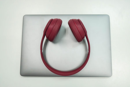 isolated notebook cute pink wireless headphone on notebook computer in workplace