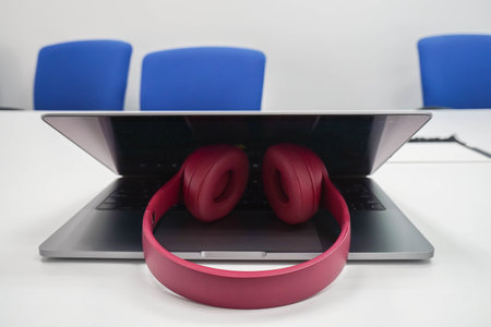 close up cute pink wireless headphone on notebook computer in office meeting room