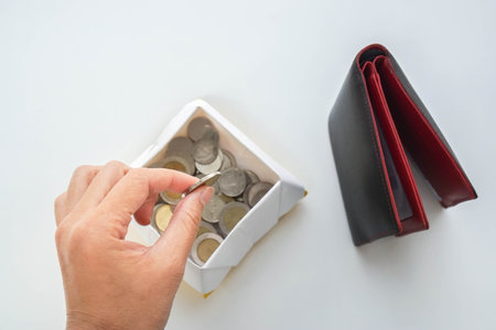 saving money concept - woman put coin from wallet in a boxの写真素材