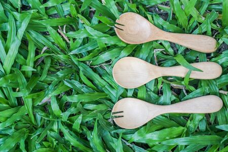 top view of wooden spoon and fork on green grass backgroundの写真素材