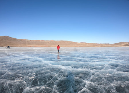 man in red winter coat walk on frozen Baikal lake in winter