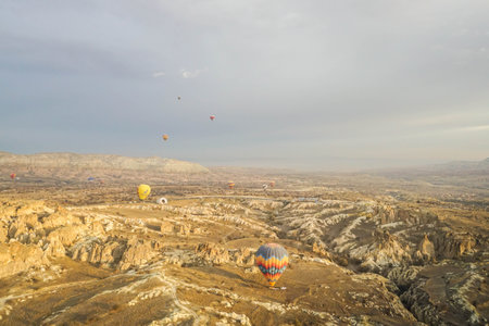 Goreme / Turkey - December 6 2019: noise and grain of mountain hill top view landscape in Cappadocia with hot air balloon in romantic sunrise momentのeditorial素材