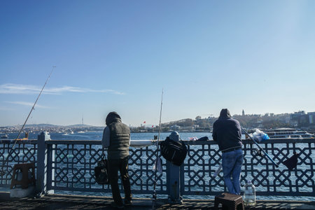 Istanbul / Turkey - December 10 2019: two men at Galata Bridge fishing to sell for livingのeditorial素材