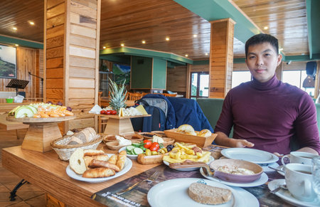 Rize / Turkey - December 2 2019: man in long sleeve on dining table in the morning in Doga Resort in holidaysのeditorial素材
