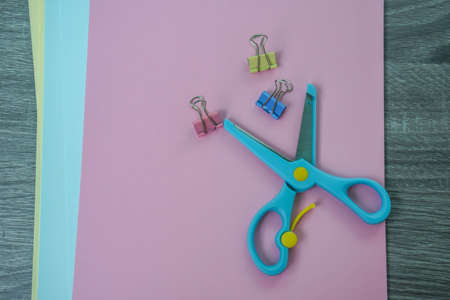 blue scissors with paper clips and colorful papers for craft workの写真素材