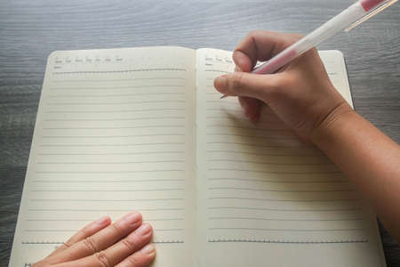 flat lay mock up woman right hand hold pen for writing to do list on notebookの写真素材