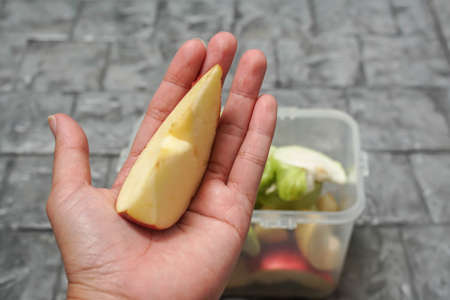 woman hand holds red apple slice for diet in dinner timeの写真素材