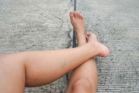 close up woman legs sit on the concrete roadの写真素材