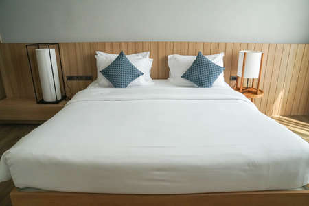 close up white mattress on minimal double bed with long big lamps at bedside in hotel bedroomの写真素材