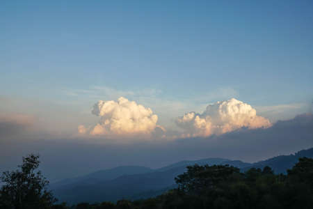 nature landscape of mountain top view with big white fluffy clouds in sunny blue skyの写真素材