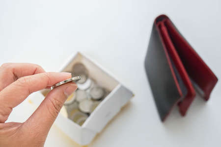 saving your money concept - woman put coin from wallet in a box for economical livesの写真素材