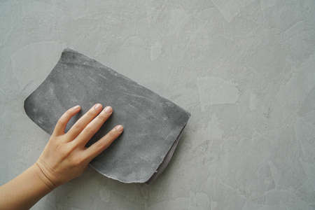 close up worker hand use sandpaper for smooth cement wall textureの写真素材