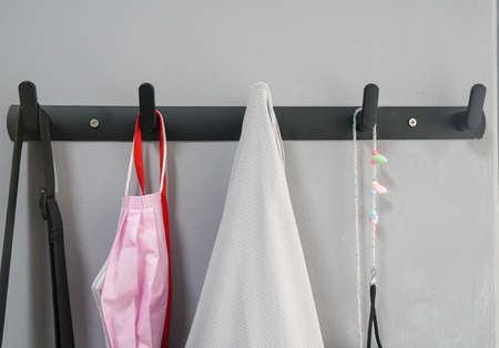 close up pink facial mask and clothing stuff hanging on the metal hookの写真素材
