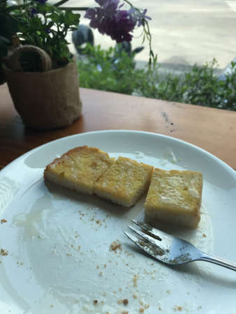 selective focus close up remaining of sliced toasted bread with butter and sweetened condensed milk on white dish after fullの写真素材
