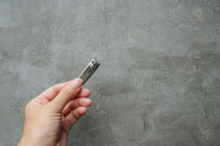 close up people hold stainless nail cutter with left hand for beauty in loft cement backgroundの写真素材