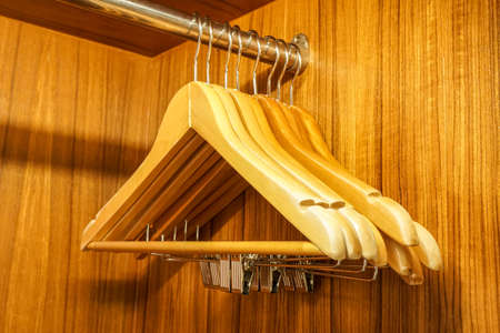 close up wooden cloth hangers in the wardrobe rail for clothes organizationの写真素材
