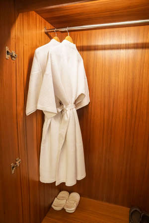 Selective focus white two bathrobes in wooden wardrobe for shower in luxury hotel bedroomの写真素材
