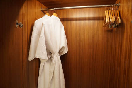 Selective focus close up white two bathrobes in wooden wardrobe for shower in luxury hotel bedroomの写真素材