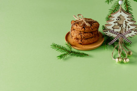 Christmas composition with chocolate chips cookies on green paper with fir tree branches and wooden...