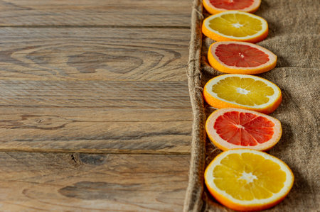 slices of citrus fruits in a row. Food background. Oranges and grapefruits on burlapの写真素材