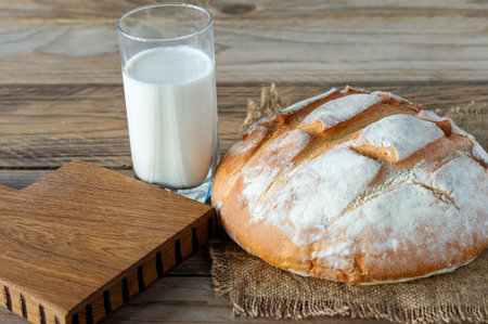 freshly baked bread on wooden gray kitchen table with glass of milk, homemade pastry