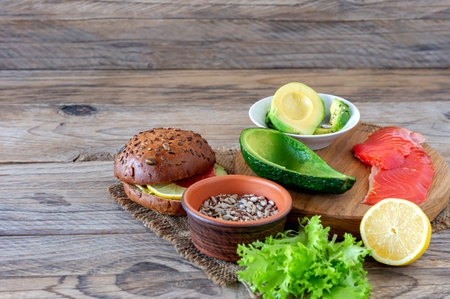 Homemade Organic Salmon Burger with tomato, corn salad and avogado on a plate on wooden backgound....