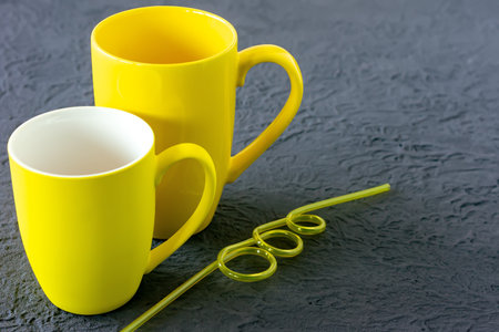 Two yellow cups on gray background. Color of the year 2021の写真素材