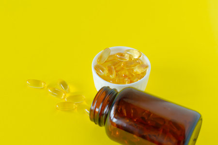 Fish oil capsules on yellow background, vitamin D, omega supplement, selective focusの写真素材