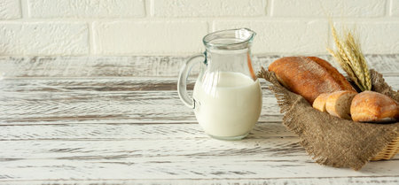 Sliced rye bread on wooden cutting board next to jug with milk. Tasty food close up. Homemade baked bread.の写真素材