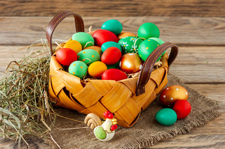 Hand-painted decorated Easter eggs in the basket on white wooden background, close up. Easter...