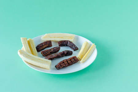 Fresh and dried bananas on a white plate. Healthy snack durin dieting.の写真素材