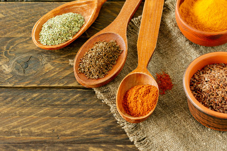 Powder spices on spoons on wooden background.