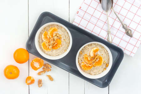 Light calorie porridge. Oatmeal with juicy tangerines and flax-free flax seeds in a bowls on sackcloth, white background. Low-calorie porridge recipeの写真素材