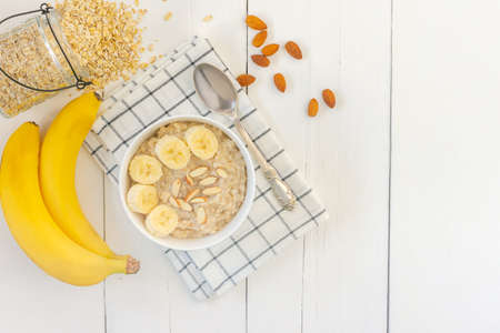 Top view of Bowl of oat flakes with sliced banana close-up on wooden table.の写真素材