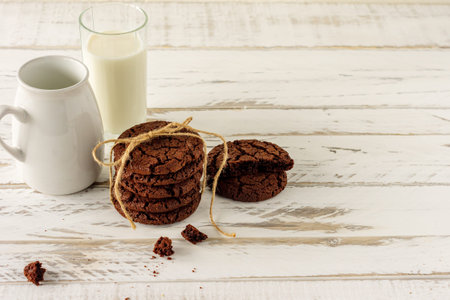 Chocolate cookies for breakfast with a glass of milk on a white wooden tableの写真素材