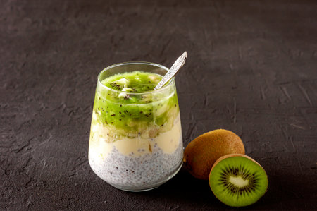 Chia seed pudding with kiwi, banana and mango. Health detox breakfast in glasses on blaxk concrete background.の写真素材