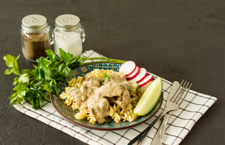 Italian whole grain pasta with roasted chicken liver and onions served on a plate on marble background.の写真素材