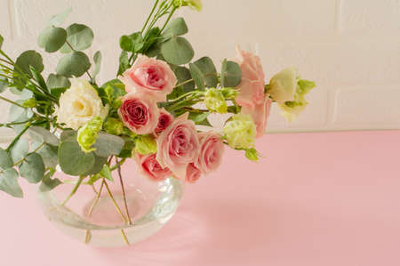 Vase with beautiful Roses, eustoma and eucalyptus flowers on table. Tender greeting card for holiday.の写真素材