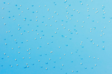 sugar sprinkles in the form of stars on blue background, congectionary decoration. copy space for...