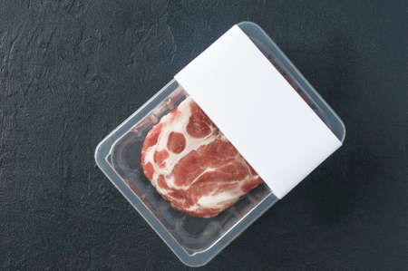 Raw marbled pork steak in vacuum packaging on black background, top view, logo mockup for design.の写真素材