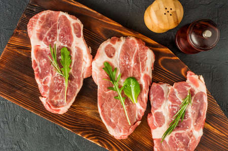 Perfect Raw Pork Neck with Spices, Ripe Tomatoes, and Fresh Leaves on Wooden Cutting Board. Top View.の写真素材