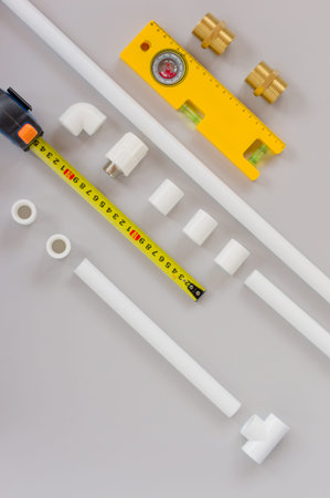 Plastic pipes for the water system, ruler and measuring level on gray background. Repair service,...